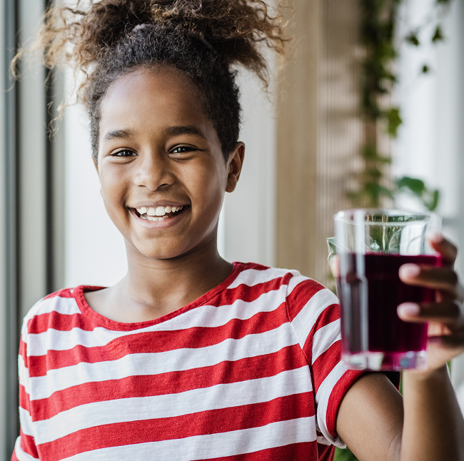 Child smiling holding a glass of SuperDay for Kids